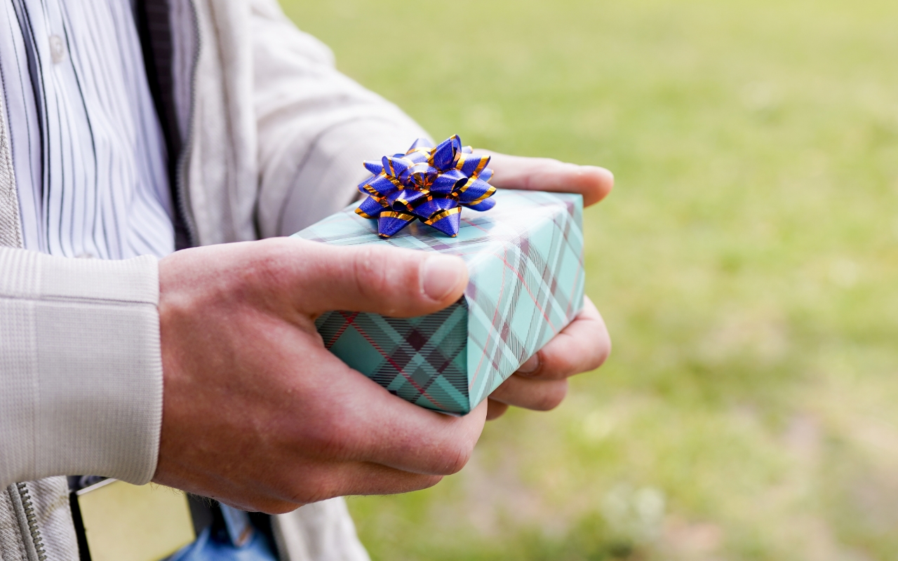 mężczyzna trzymający pudełko z prezentem w rękach